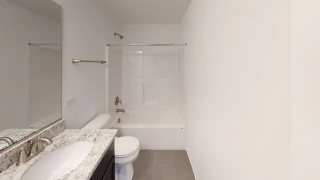 a bathroom with a granite countertop sink a toilet and shower