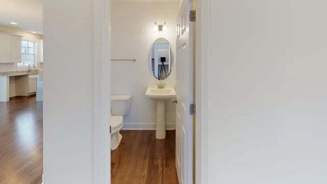 a view of a hallway with wooden floor and a bathroom