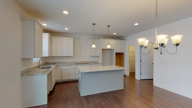 a large kitchen with granite countertop a large counter top a sink stainless steel appliances and cabinets
