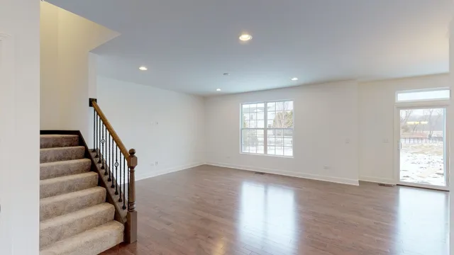 a view of an empty room with wooden floor and fan