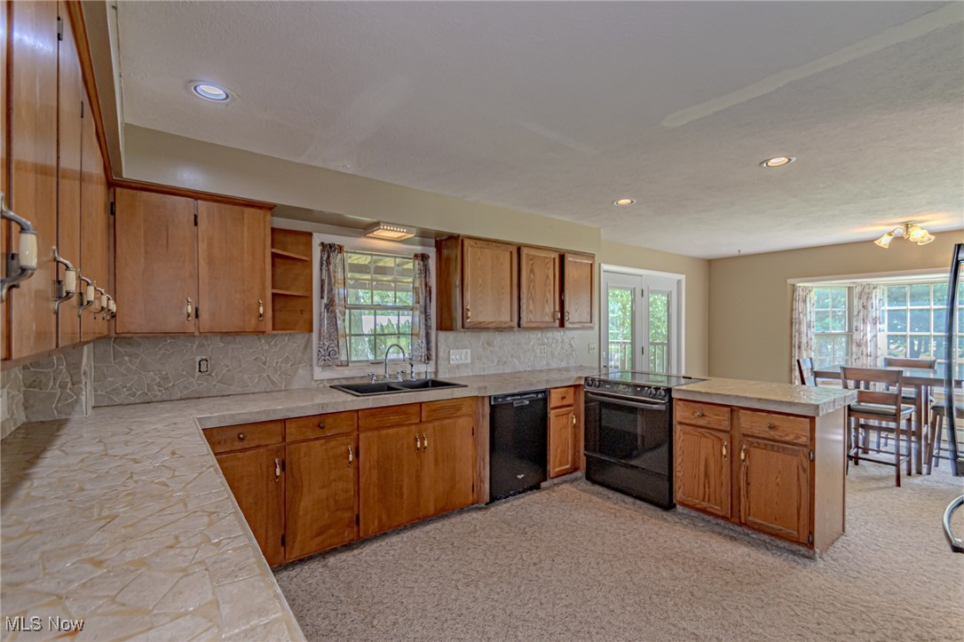 749 Hartman Road Wadsworth, OH 44281 - Photo 26 of 49 Kitchen with sink, decorative backsplash, light carpet, kitchen peninsula, and black appliances