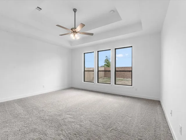 an empty room with chandelier fan and windows