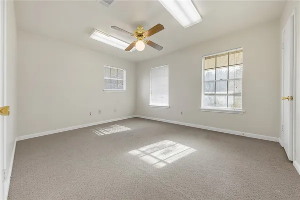 an empty room with windows and ceiling fan