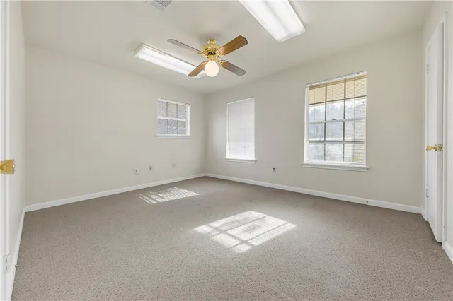 an empty room with windows and ceiling fan