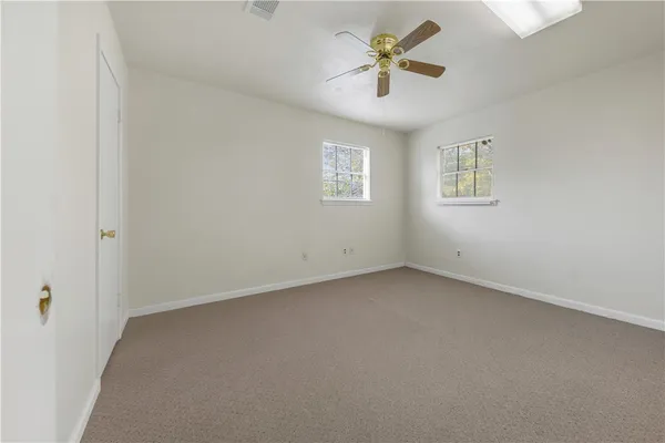 an empty room with a view of a ceiling fan and window
