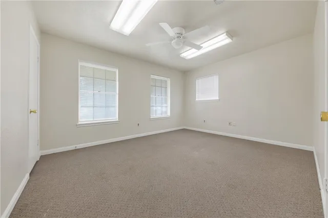 an empty room with windows and fan
