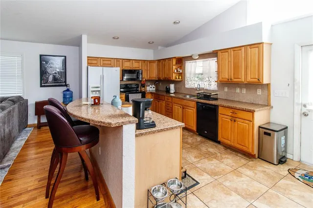 a kitchen with stainless steel appliances granite countertop table chairs sink and wooden cabinets