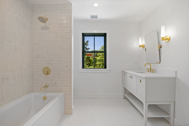 a bathroom with a bathtub a sink a window and mirror