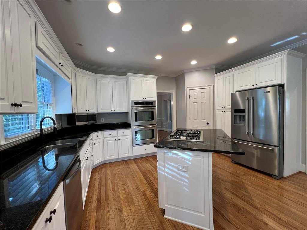 Undisclosed Address Kennesaw, GA 30144 - Photo 12 of 51 a kitchen with kitchen island granite countertop a refrigerator a stove a sink dishwasher and a microwave with wooden floor