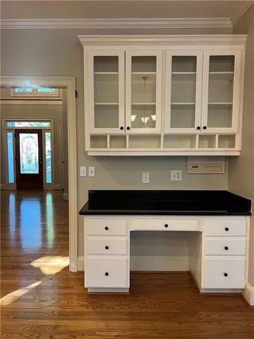 a living room with white cabinets and wooden floor