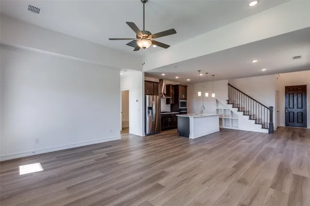 a view of a kitchen with a ceiling fan hardwood floor and a ceiling fan