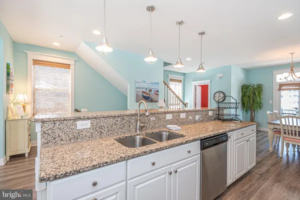 a kitchen with stainless steel appliances kitchen island granite countertop a dining table chairs refrigerator and sink