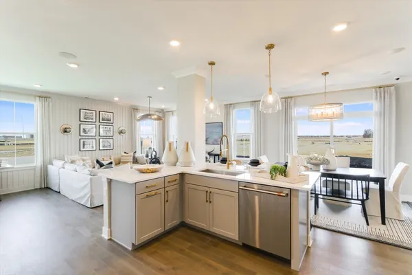 a large white kitchen with a stove a sink dishwasher and a dining table with wooden floor