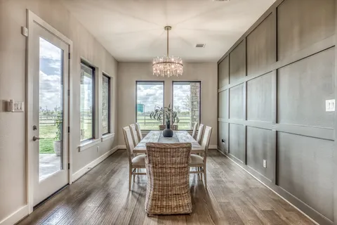 a dining room with furniture large windows a chandelier and wooden floor