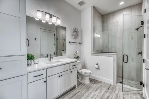 a bathroom with a double vanity sink a toilet and shower