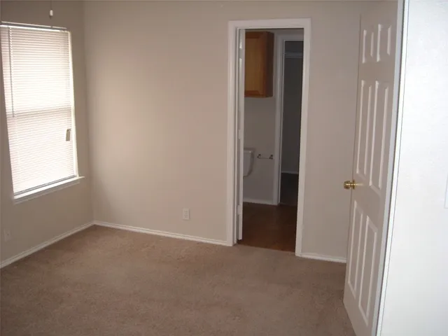 a view of an empty room with closet and a window