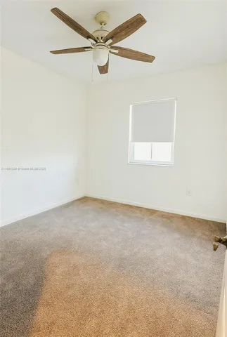 an empty room with a window and a fan