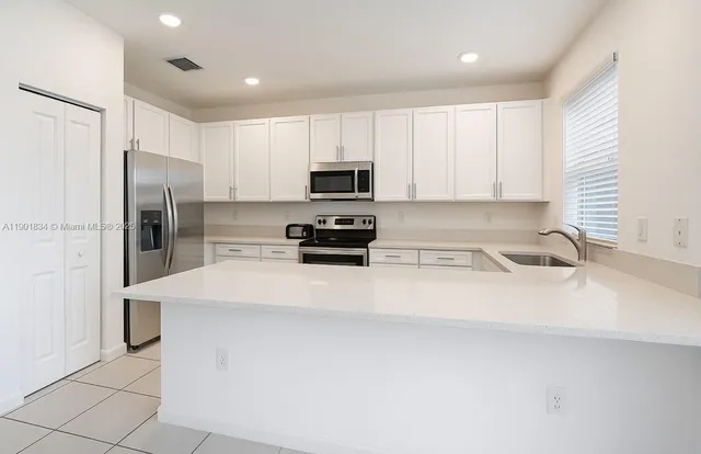 a kitchen with stainless steel appliances a refrigerator sink and white cabinets