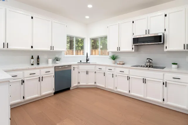 a kitchen with cabinets appliances a sink and a window