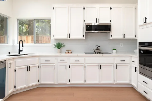 a kitchen with white cabinets and window