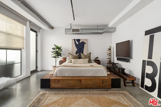 a spacious bedroom with a bed and a flat screen tv