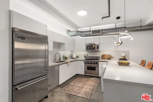 a kitchen with stainless steel appliances granite countertop a refrigerator and a stove top oven