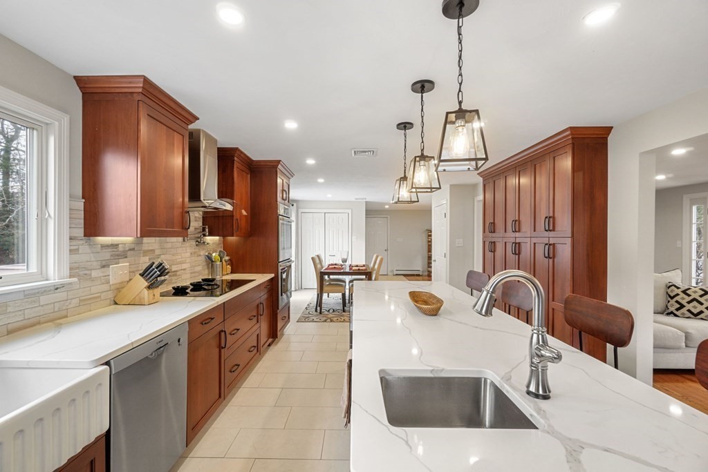 60 Hitching Post Drive Walpole, MA 02081 - Photo 9 of 37 a large kitchen with stainless steel appliances a stove a sink a oven a dining table and chairs with wooden floor