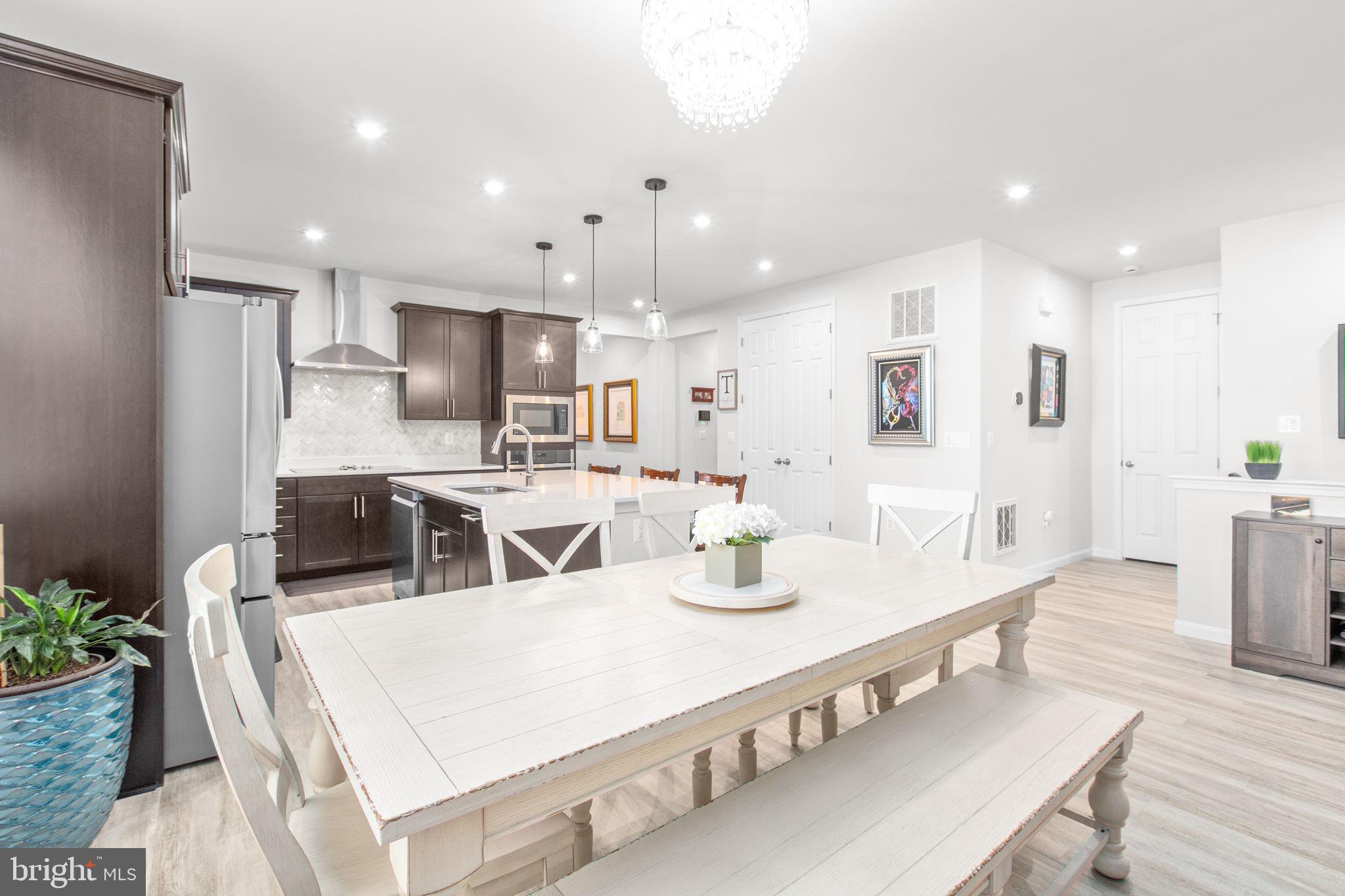 6306 Bobcat Lane King George, VA 22485 - Photo 7 of 58 a large kitchen with stainless steel appliances kitchen island granite countertop a dining table chairs and a refrigerator