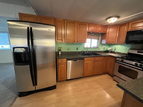 a kitchen with stainless steel appliances granite countertop a stove a sink and a refrigerator