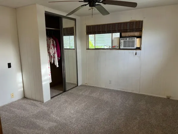 an empty room with windows and fan