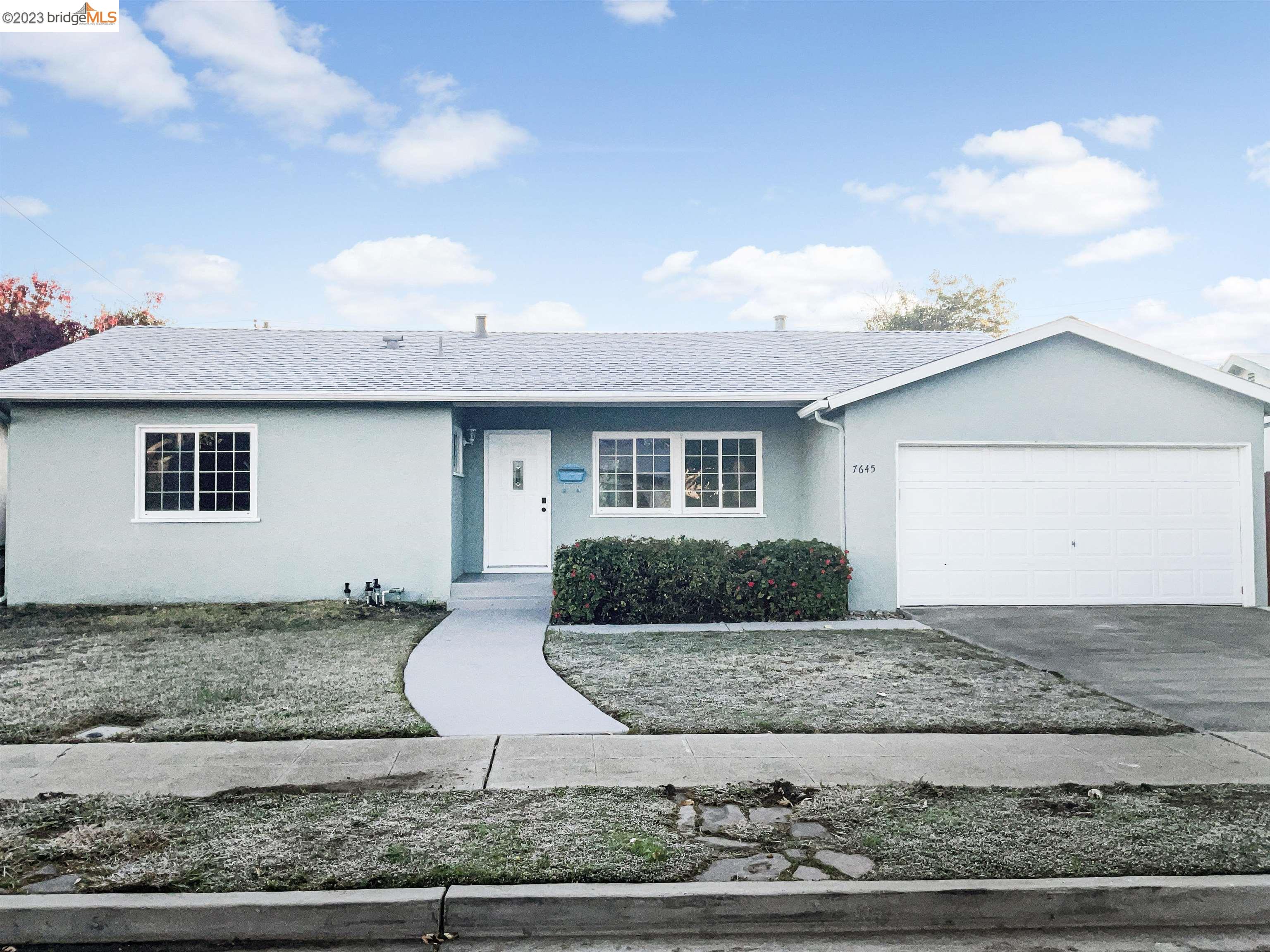 a view of a house with backyard and trees in the background