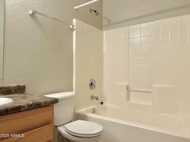 a bathroom with a granite countertop bathtub shower sink vanity and toilet