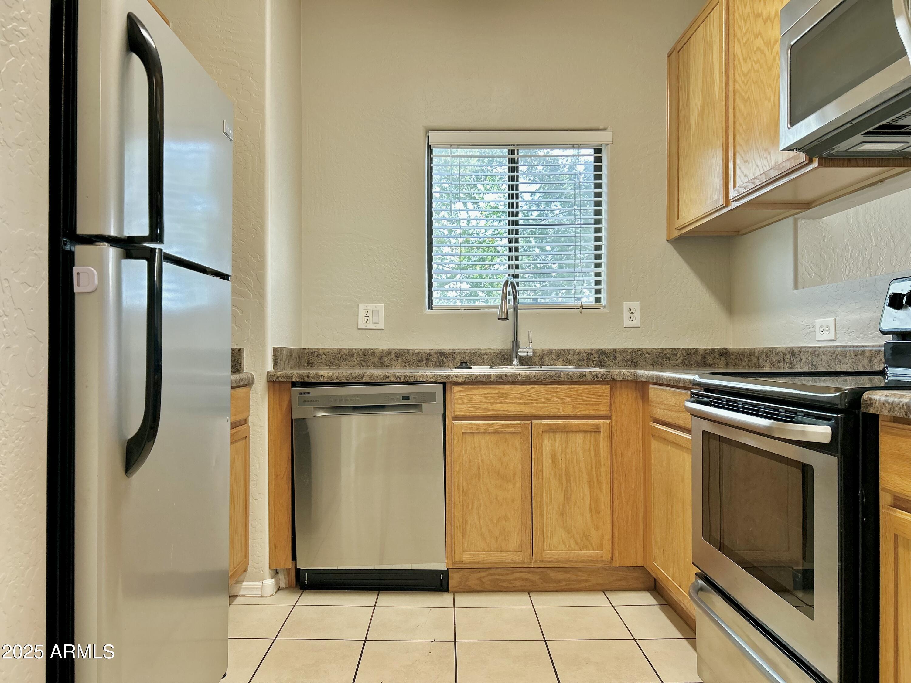 4423 East McLellan Road, Unit 115 Mesa, AZ 85205 - Photo 5 of 16 a kitchen with granite countertop a refrigerator and a sink