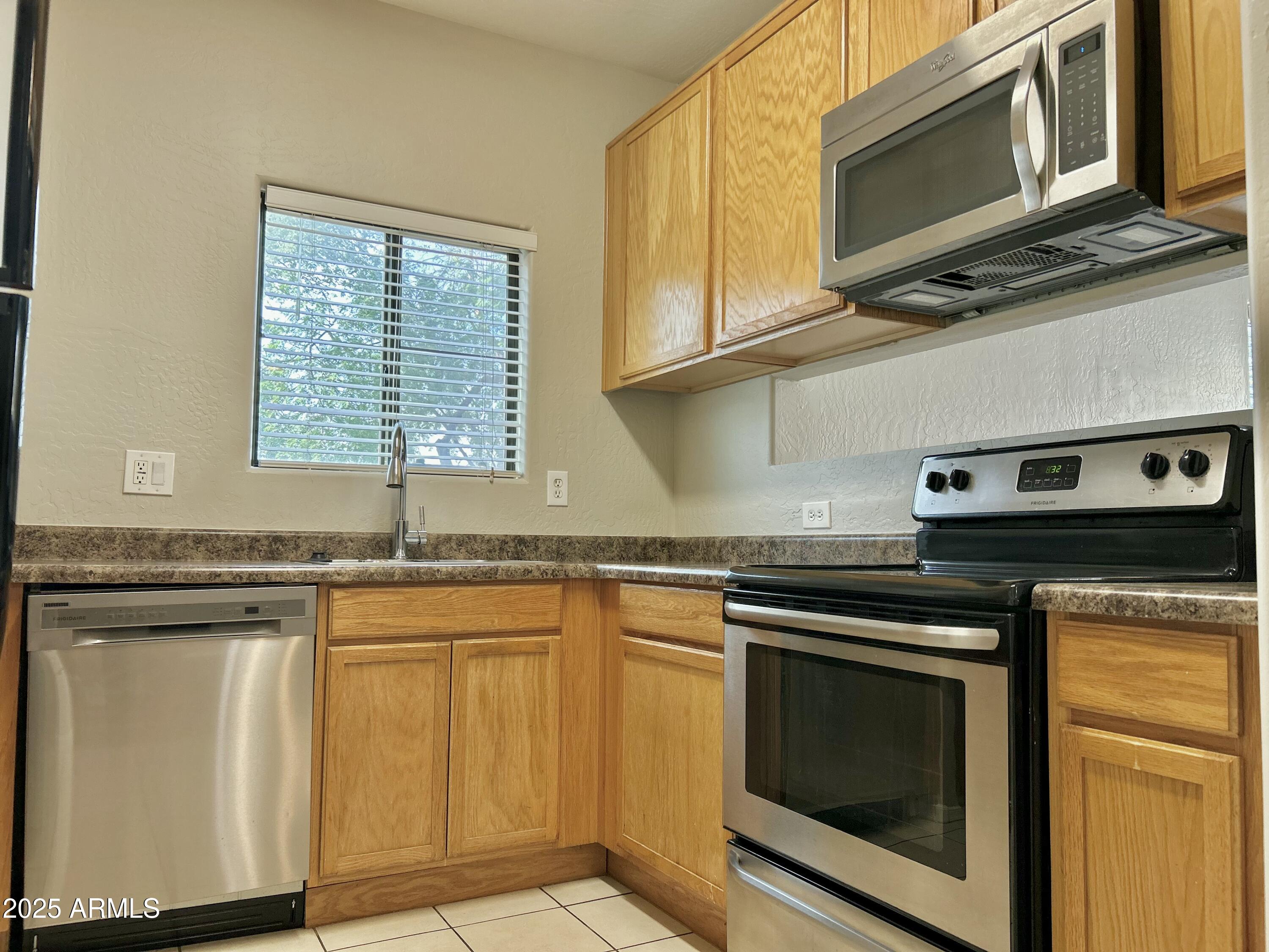 4423 East McLellan Road, Unit 115 Mesa, AZ 85205 - Photo 7 of 16 a kitchen with stainless steel appliances granite countertop a stove microwave and cabinets