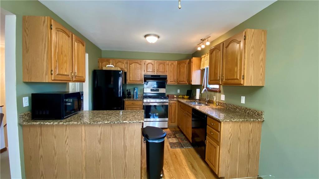 200 Porter Street Springdale, PA 15144 - Photo 9 of 35 a kitchen with granite countertop a refrigerator a stove a sink dishwasher and wooden cabinets