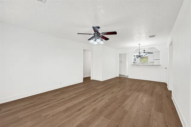 an empty room with wooden floor and ceiling fan