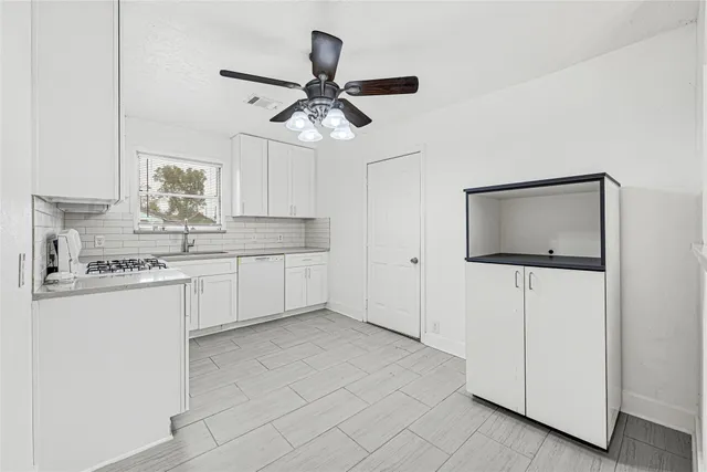 a kitchen with kitchen island white cabinets appliances and a counter top space