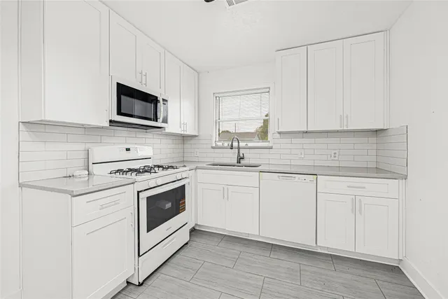 a kitchen with white cabinets and white appliances