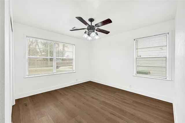 a view of an empty room with a window and wooden floor