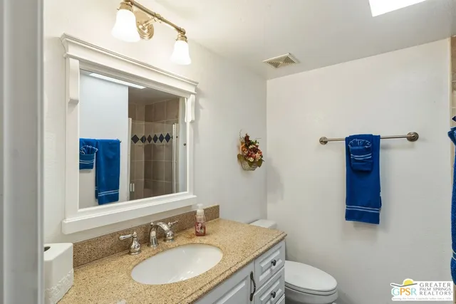 a bathroom with a granite countertop sink mirror vanity and toilet
