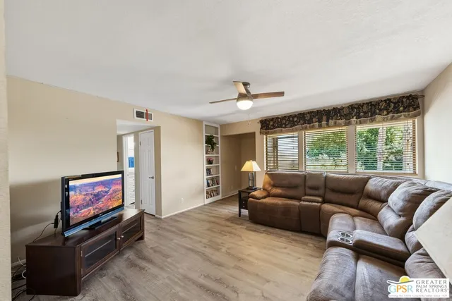 a living room with furniture flat screen tv and a large window