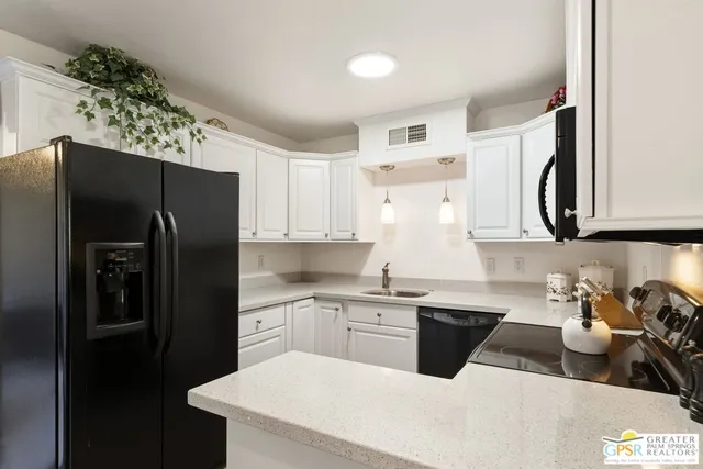 a kitchen with a sink dishwasher a refrigerator and cabinets
