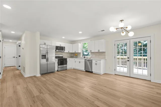 a large white kitchen with wooden floors and white cabinets