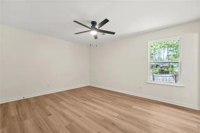 an empty room with wooden floor fan and windows