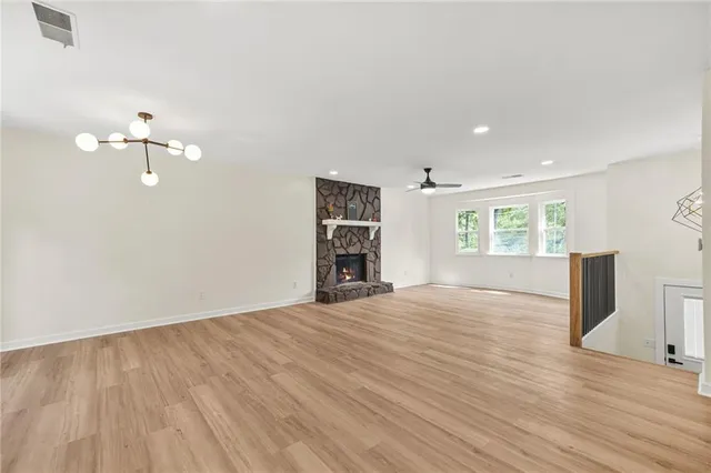 an empty room with wooden floor chandelier and windows