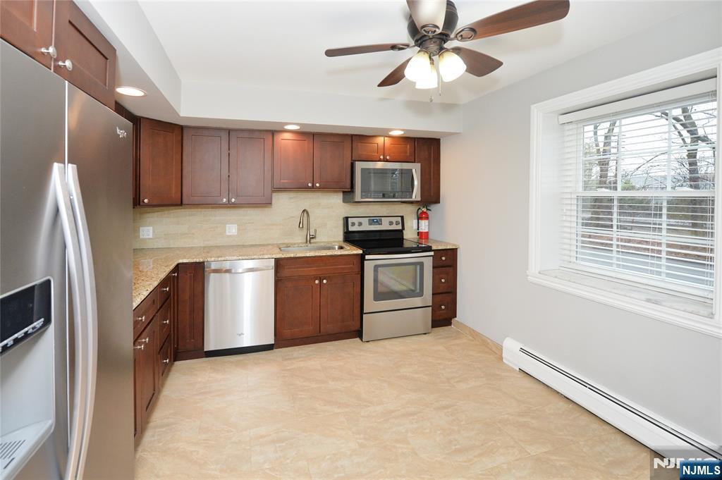 21-31 Ridge Road, Unit D15 Ridgewood, NJ 07450 - Photo 3 of 16 a kitchen with stainless steel appliances granite countertop a stove top oven a refrigerator a sink and dishwasher with wooden floor