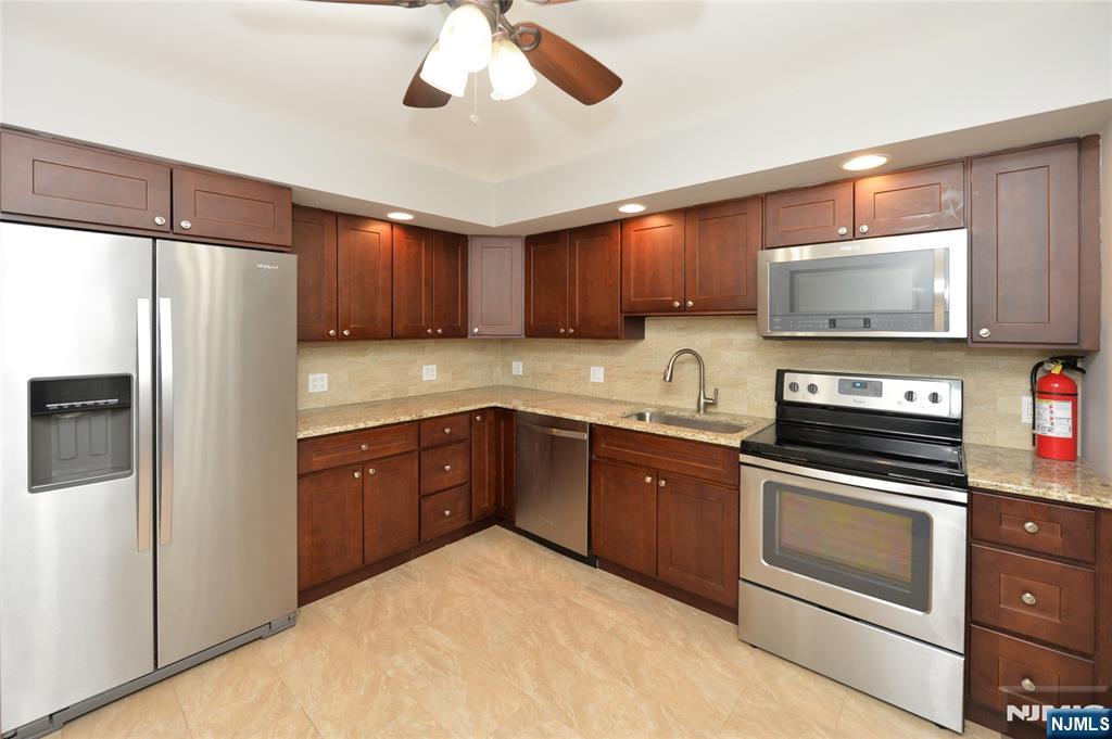21-31 Ridge Road, Unit D15 Ridgewood, NJ 07450 - Photo 4 of 16 a kitchen with stainless steel appliances granite countertop a refrigerator a stove and a sink with wooden floor