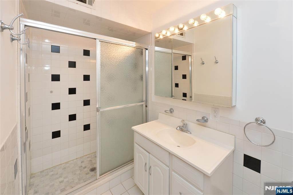 21-31 Ridge Road, Unit D15 Ridgewood, NJ 07450 - Photo 10 of 16 a bathroom with a sink a toilet a mirror and shower