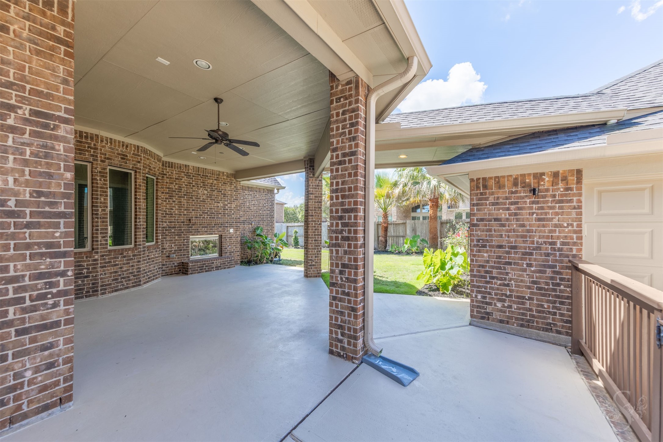 5803 Mustang Ridge Lane Fulshear, TX 77441 - Photo 38 of 48 Expansive covered patio offers a spacious outdoor living area with ceiling fan, recessed lighting and a beautiful brick fireplace for year-round enjoyment. The covered breezeway connection to the detached garage adds convenience while creating a private courtyard-style setting.