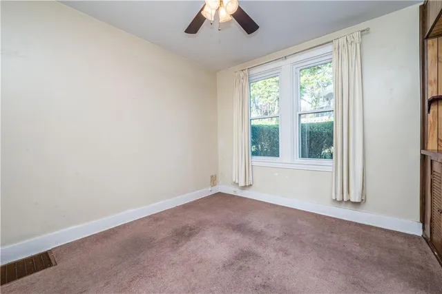 an empty room with a window and a ceiling fan